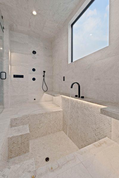 Zbranek Holt LakeLBJ Modern Luxury Lakehouse Primary Bathroom Soaking Tub Walk in Shower Herringbone Tile Backlit Feature
