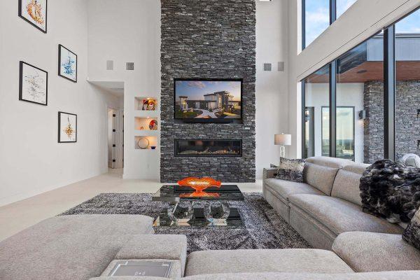 Modern Luxury Hill Top living room stacked stone fireplace built in shelves gray sectional Zbranek and Holt Custom Homes