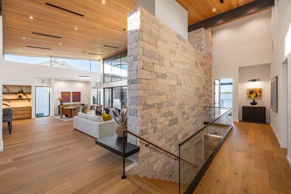 Modern Organic Lakehouse Living Area Stone Wall Wood Ceiling Glass Railing Zbranek and Holt Custom Homes