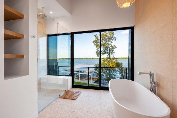 Modern Organic Lakehouse Master Bathroom Freestanding Tub Walk In Shower Floor to Ceiling Windows Water View Zbranek and Holt Custom Homes