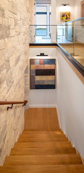 Modern Organic Lakehouse Staircase Stone Wall Glass Railing Wood Steps Zbranek and Holt Custom Homes