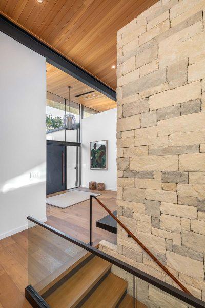 Modern Organic Lakehouse Staircase Stone Wall Wood Ceiling Glass Rail Zbranek and Holt Custom Homes